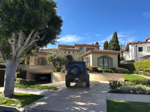 A House With A Car Parked In Front, Showcasing A Suburban Setting With A Well-Maintained Lawn.