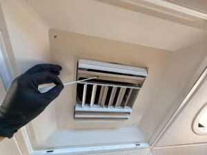 Close-Up Of Hvac Vent During Mold Inspection At An Irvine Commercial Property, Showing Mold Inspection Equipment And Technician'S Hand Checking Air Vent For Contamination