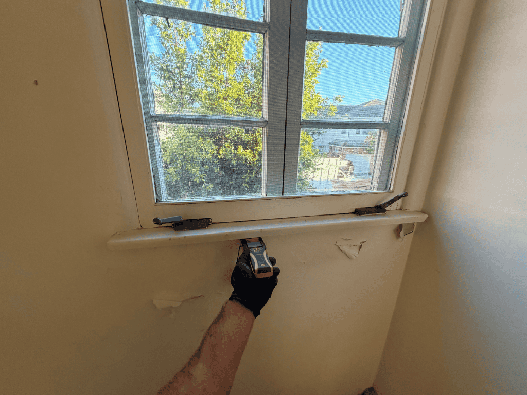 An Individual Using A Tool To Fix A Window, Demonstrating A Hands-On Repair Process