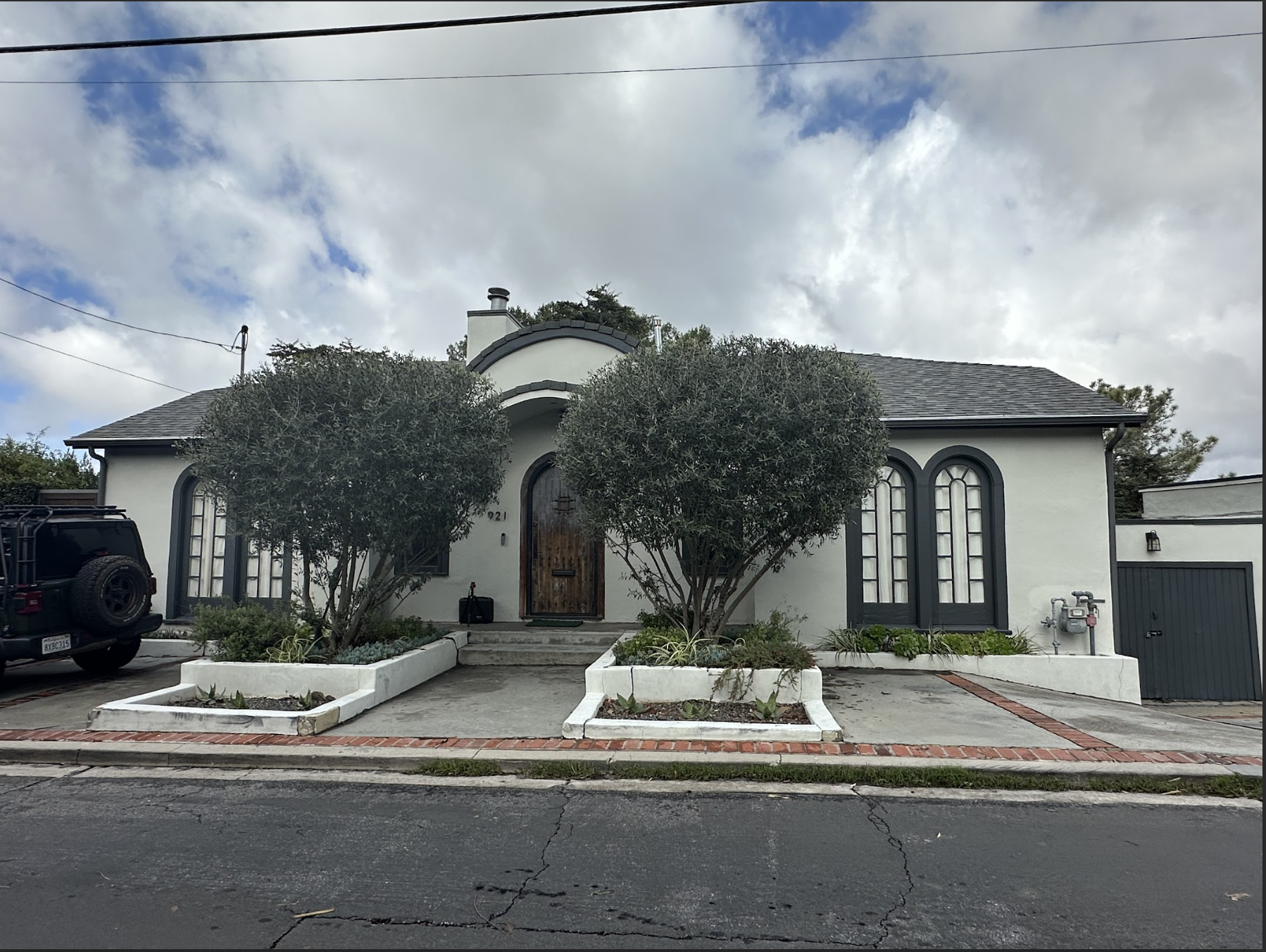 User-Inserted A White Exterior House With A Black Roof, Featuring Two Black Cars Parked In Front.