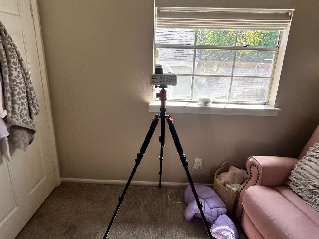 User-Inserted Indoor Air Quality Testing Equipment Set Up Near A Bedroom Window To Assess Possible Water Intrusion And Moisture Concerns.